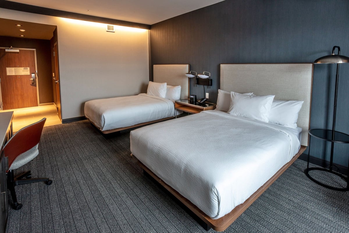 A hotel room with two beds, a desk, and a chair.