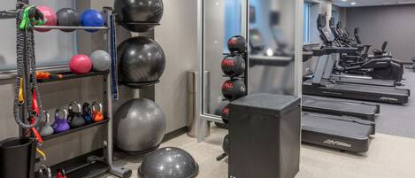 A gym with exercise equipment, including kettlebells, medicine balls, and treadmills.