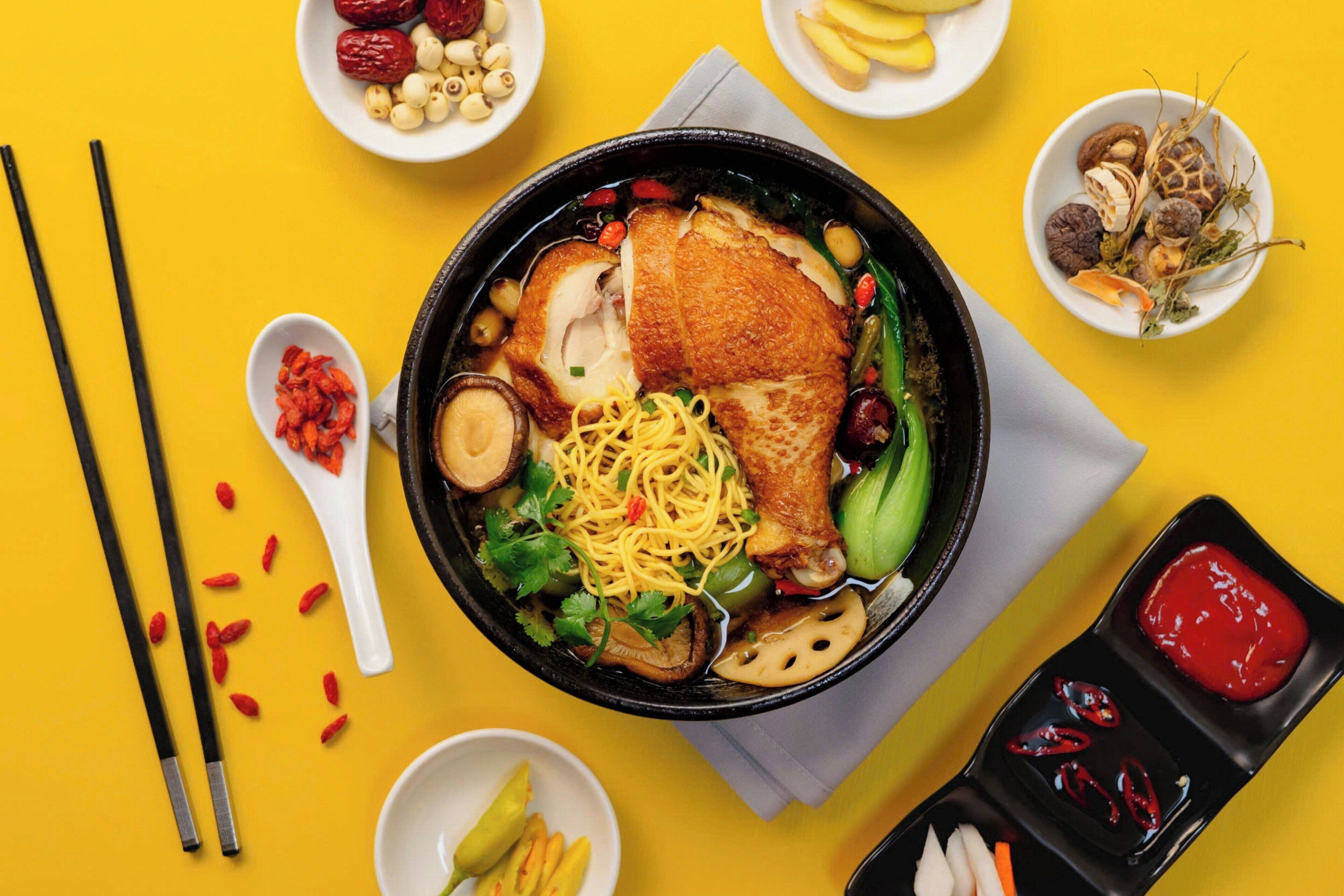 Una ciotola di noodles con diversi condimenti e una porzione di salsa da intingere.