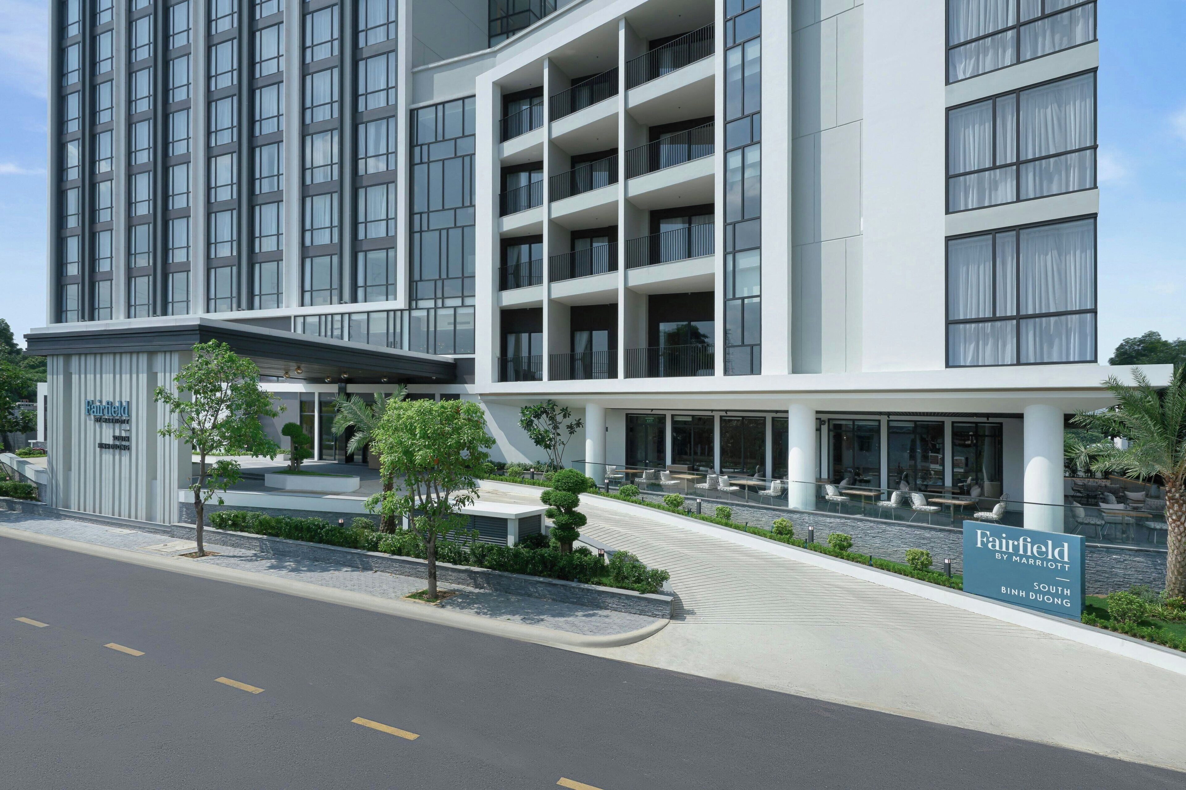 Un hotel moderno con una estructura de varios pisos, un área de estar al aire libre y un cartel que indica que es Fairfield by Marriott South Binh Duong.