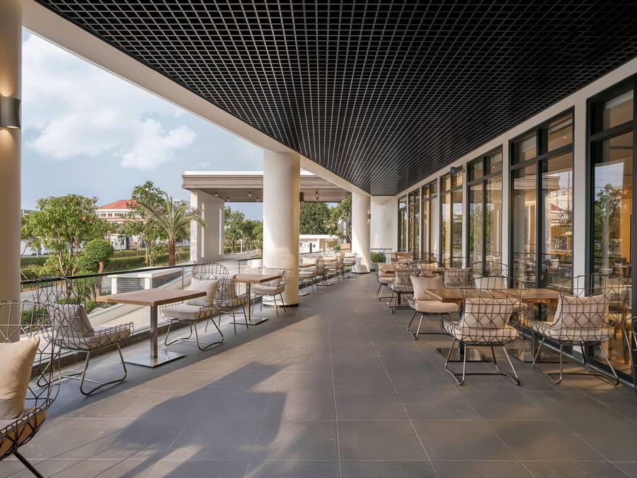 Un café en plein air doté de mobilier moderne et de grandes fenêtres offrant une vue sur les environs.