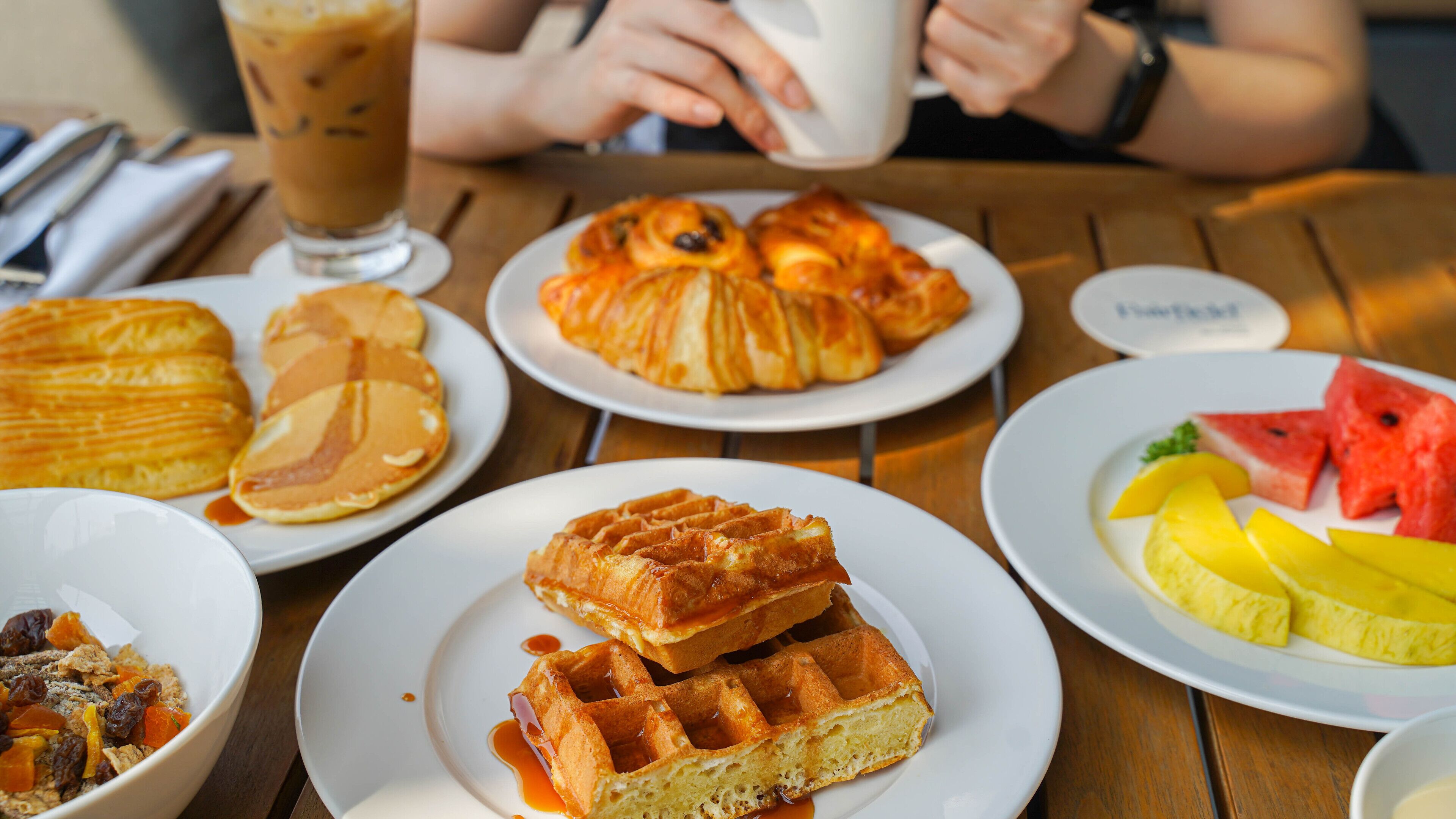 A breakfast table with waffles, pastries, and fruit.