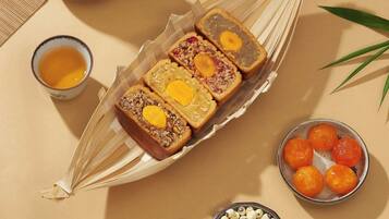 A tray of mooncakes, a teapot, a bowl of tea, and a woven basket with more mooncakes.