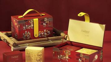 A collection of red gift boxes with yellow handles, a tea set, and a bamboo flute.