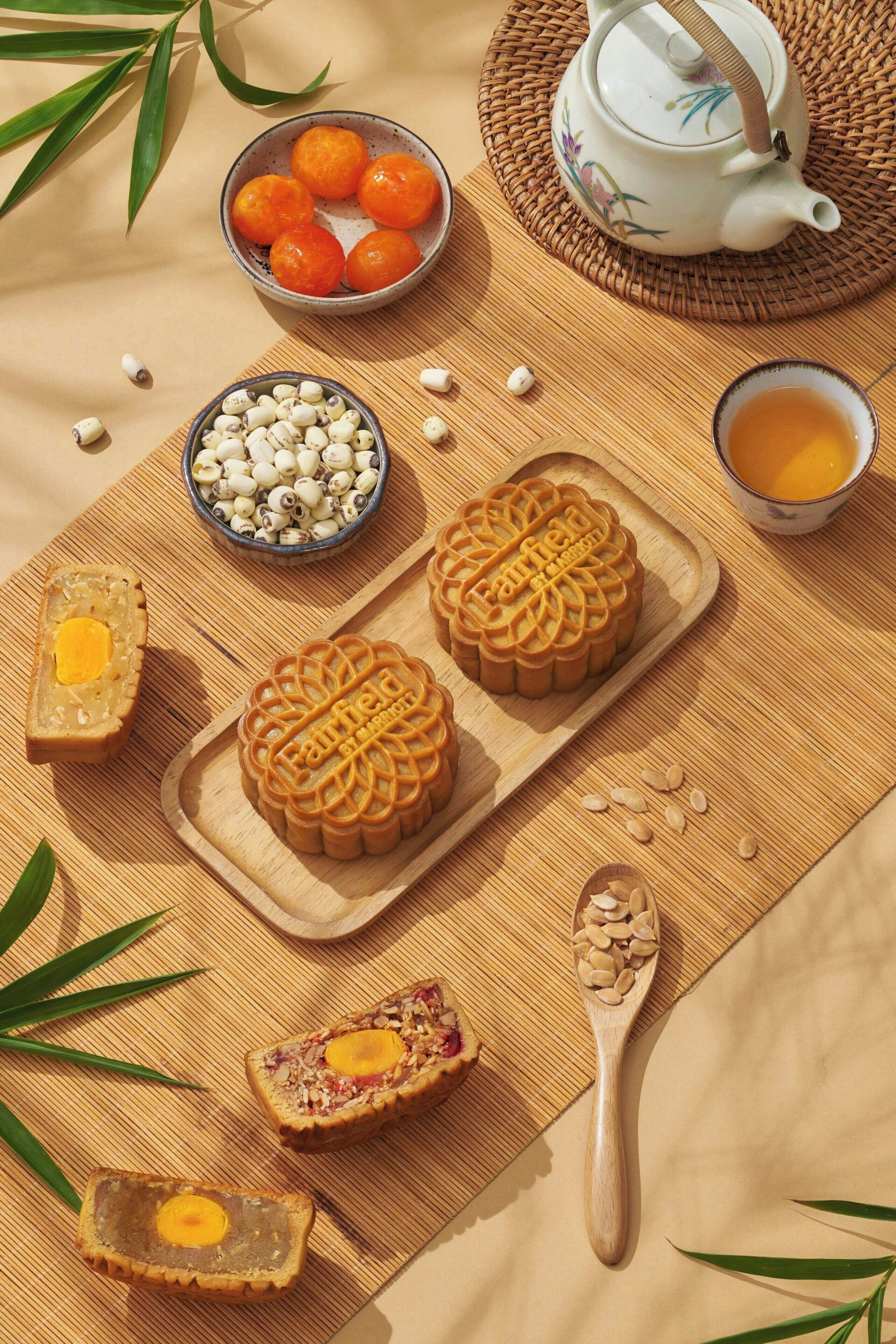 A table setting with mooncakes, a teapot, and a bowl of oranges.