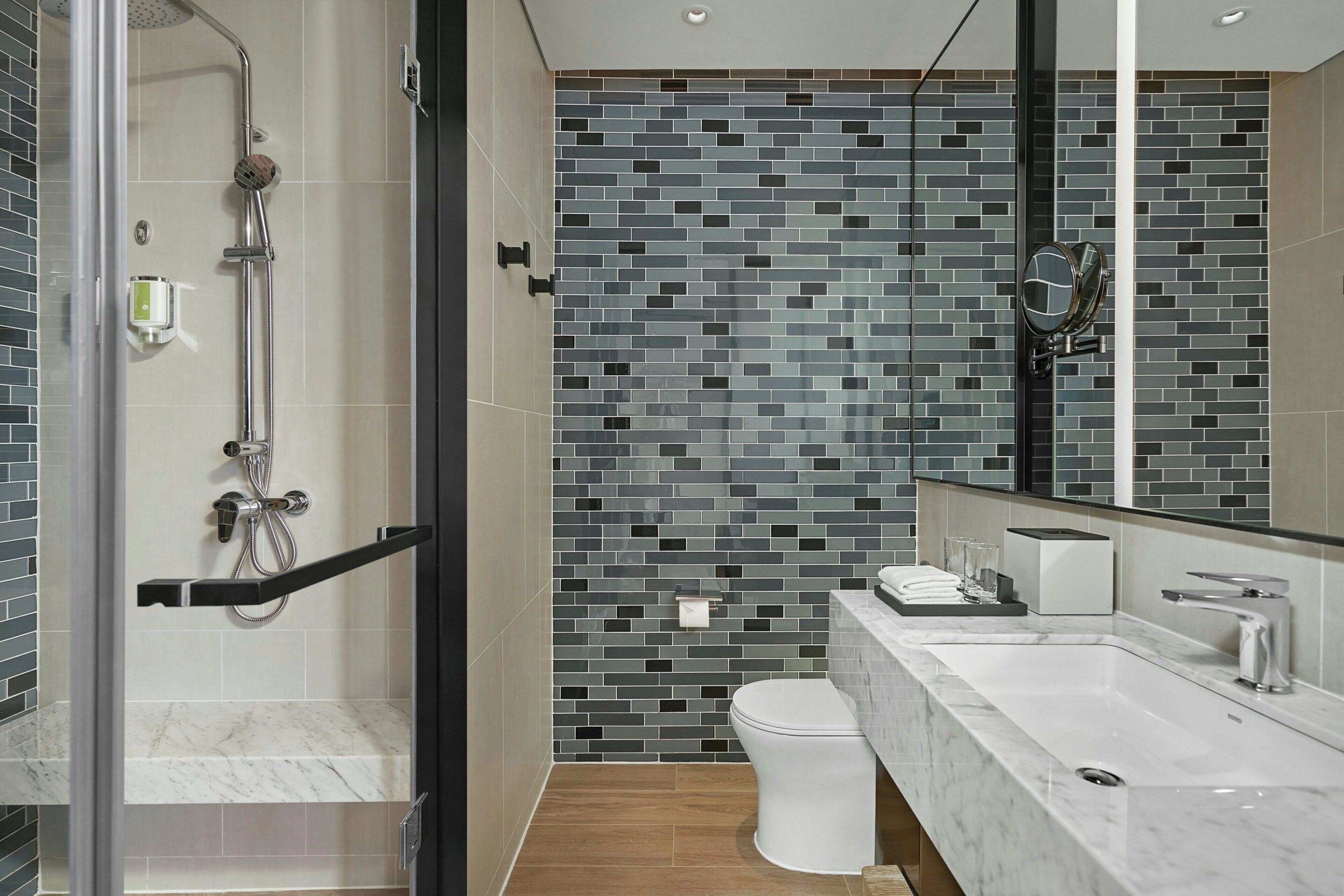 A modern bathroom with a glass-enclosed shower, a white toilet, and a marble sink.
