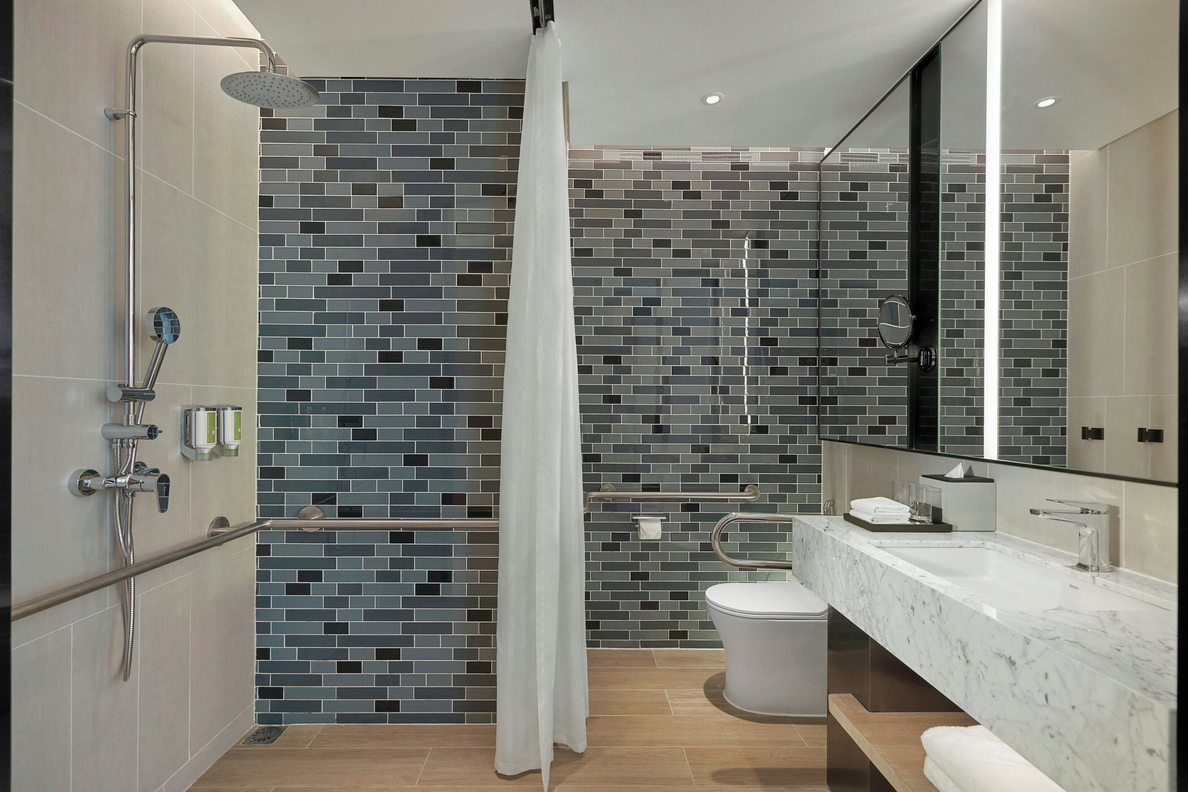 A modern bathroom with a shower, toilet, and sink.
