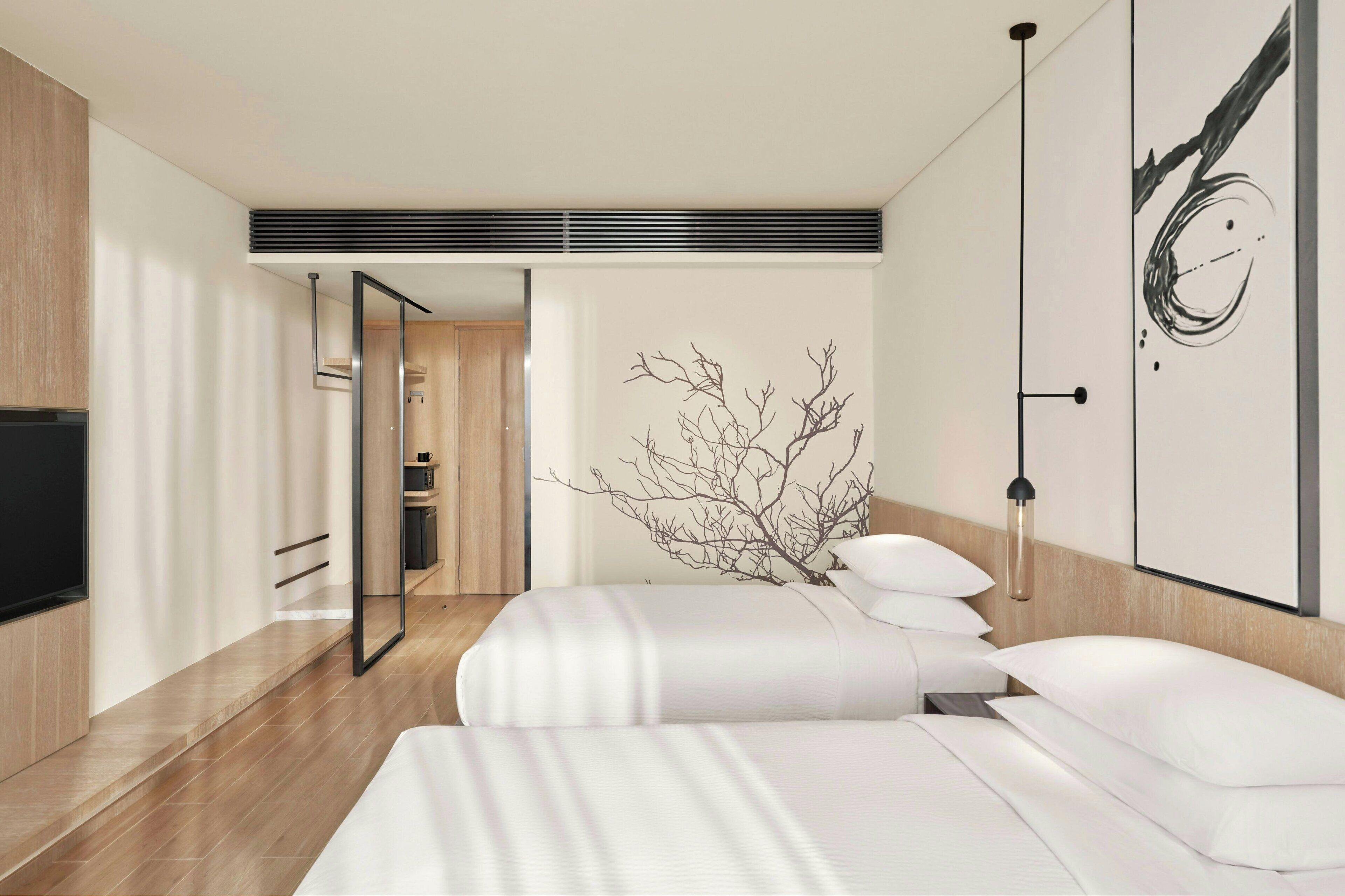 A modern hotel room with a large bed, a flat-screen TV, and a minimalist decor.
