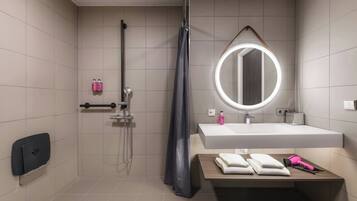 Un baño moderno con ducha, lavamanos con espejo y un perchero para toallas.
