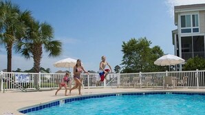 A swimming pool with a white fence, lounge chairs, and umbrellas. - 3 Bedrm, 2 Bath Ground-floor Lake-side, 5 min walk to beach. Great for families! (North Myrtle Beach)