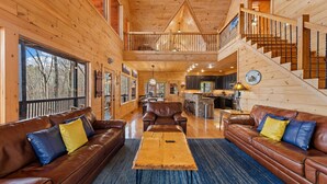 A spacious wooden cabin interior with a dining area, kitchen, and a staircase leading to a loft. - Cabin in the Clouds, Best Views, Hot Tub, Games, Firepit, Pets, Flat Paved Drive (Mineral Bluff)