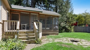 A house with a covered porch, a stone fire pit, and a wooden deck. - Union Pier Home With Hot Tub and One Block To Beach! (Union Pier)