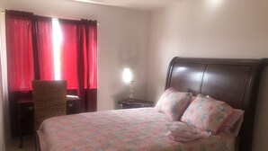 A bedroom with a bed, a chair, a nightstand, and a lamp.