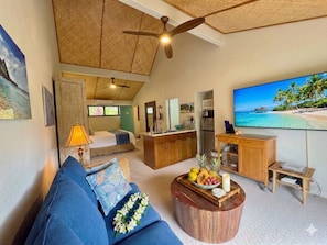 Un espacio habitable compacto con kitchenette, zona de comedor y área de estar con televisor.