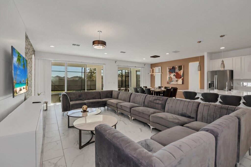 A modern living room with a sectional sofa, a coffee table, and a TV mounted on the wall.
