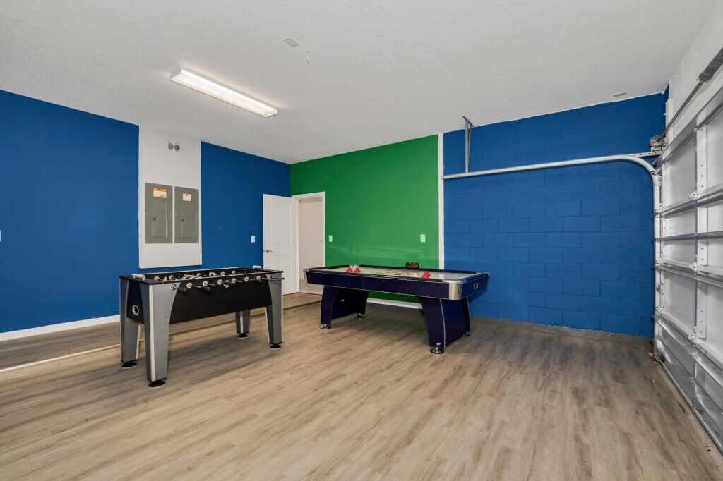 Une pièce équipée de deux tables de baby-foot, d’un fond vert et d’un mur bleu.