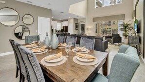A spacious dining area with a large wooden table set for six, surrounded by upholstered chairs.