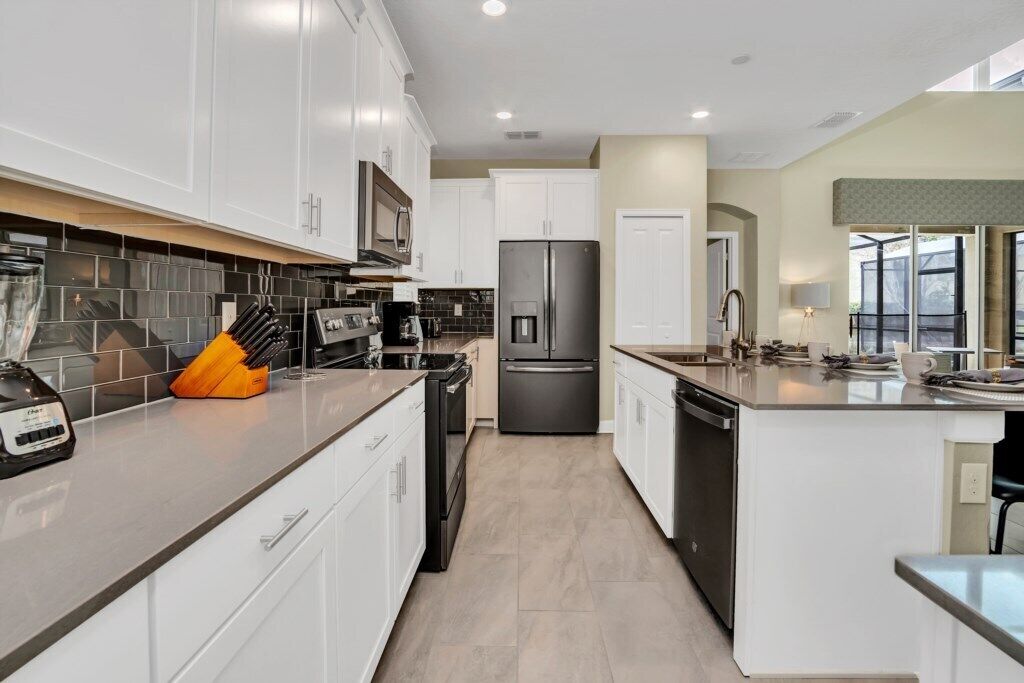 A modern kitchen with white cabinets, a stainless steel refrigerator, and a coffee maker.