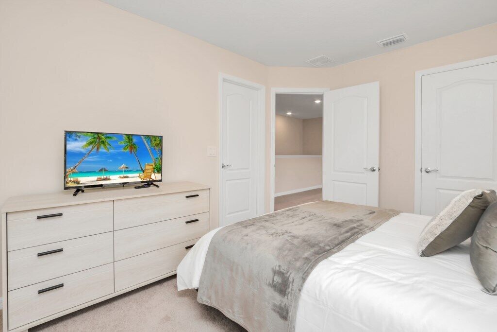 A bedroom with a bed, a TV on a dresser, and a closet.