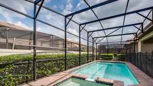 A swimming pool with a glass enclosure, surrounded by a brick patio and greenery. - Ultimate 8 Bedroom 6 Bathroom Windsor At Westside Resort Villa (Kissimmee)