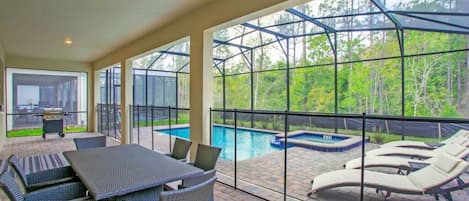 Un patio exterior con piscina, sillas de descanso y una mesa con sillas.