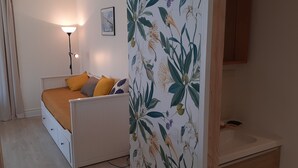 Un dormitorio con cama, lámpara de noche y baño con lavabo y espejo.