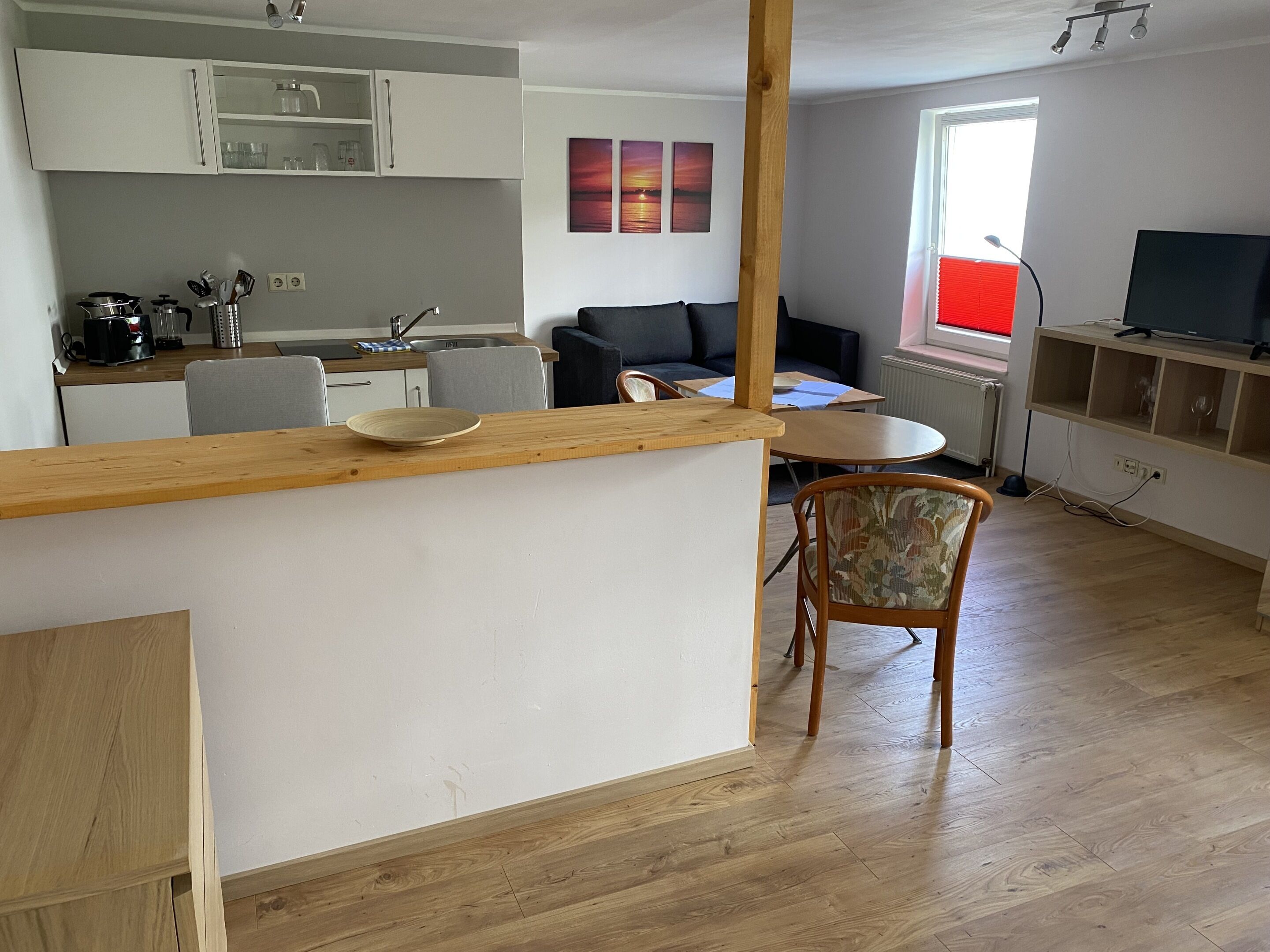A modern kitchen with white cabinets, a wooden island, and a dining area with a sofa and table.
