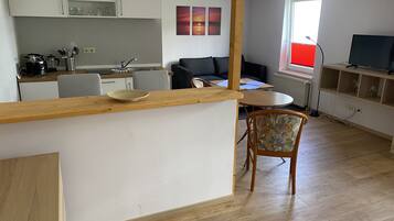 A modern kitchen with white cabinets, a wooden island, and a dining area with a sofa and table.
