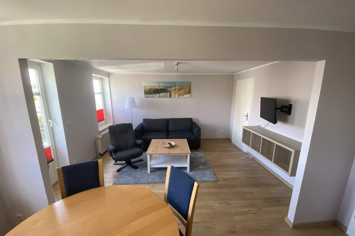 Una sala de estar con un sofá, una mesa de centro y un televisor montado en la pared.
