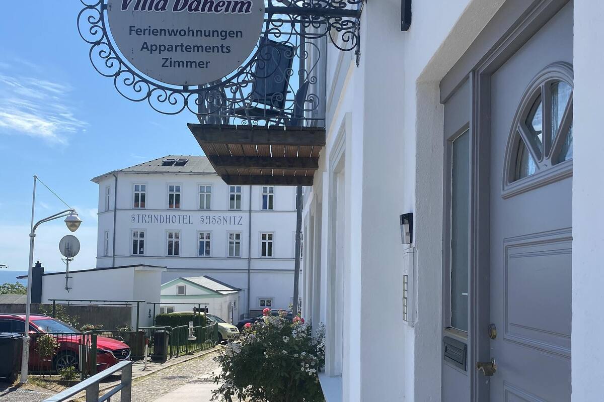 Un edificio con un letrero que dice "Pension Villa Daheim" y "Ferienwohnungen Apartments Zimmer".