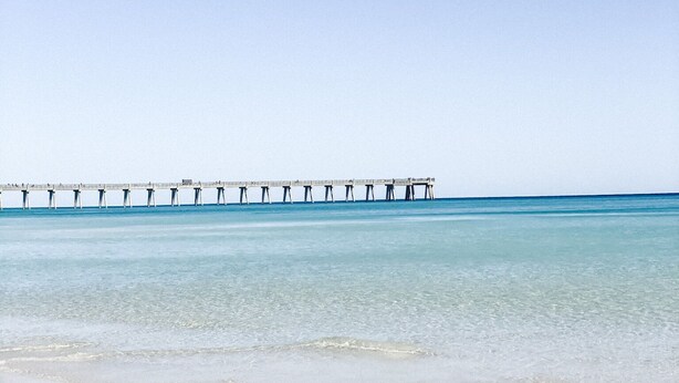 Una playa con un muelle que se adentra en el agua.