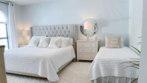 Un dormitorio con dos camas, un ventilador de techo, una mesita de noche, un espejo y una alfombra.