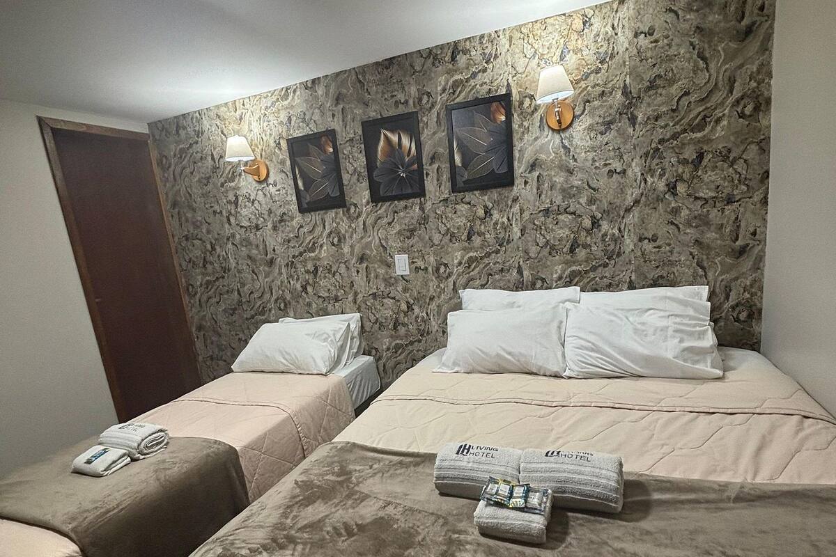 A hotel room with two beds, a marble-patterned wall, and a ceiling light.