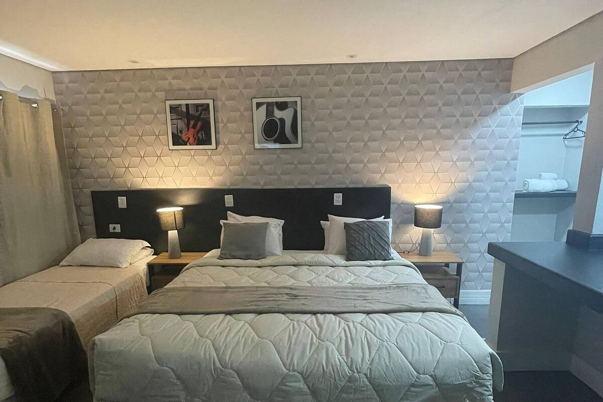 A hotel room with a large bed, two bedside tables with lamps, a headboard, and a geometric-patterned wall.