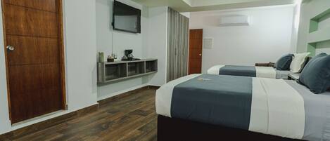 A bedroom with two beds, a wooden door, a mounted TV, and a built-in shelf.