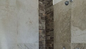 Una ducha con pared de piedra y suelo de baldosas.