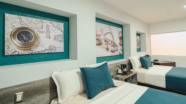 Habitación de hotel con dos camas, un mapa, una brújula y una ventana con vistas.