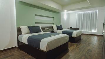 Ein Hotelzimmer mit zwei Betten, einem Schreibtisch und einem Fenster mit Vorhängen.