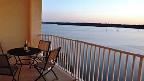 A balcony with a table and chairs overlooking a calm body of water during sunset. - Sky view of sunsets and TAMPA BAY !! (St. Petersburg)