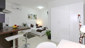 Un salon moderne avec un canapé, un coin repas doté d’un bar et une grande armoire.