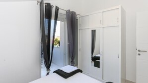 A bedroom with a bed, a wardrobe, and a mirror. - Apartment in Tribunj with Seaview, Balcony, Air condition, WIFI (4953-4) (Tribunj)