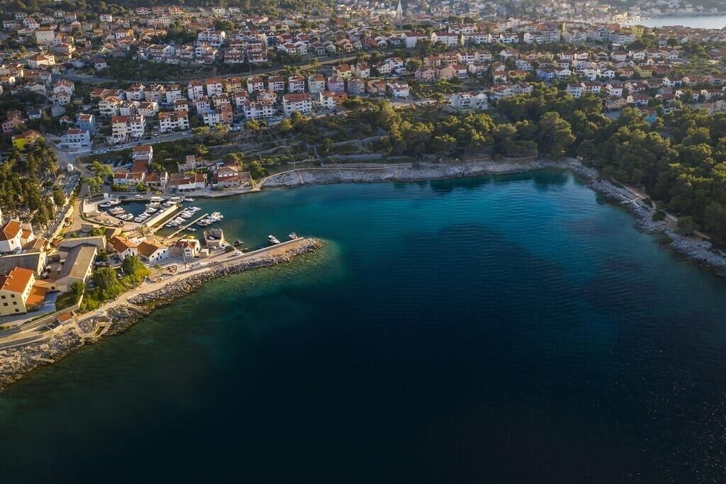 Vue aérienne d’une ville côtière avec des immeubles résidentiels, une marina et un port aux eaux d’un bleu limpide.