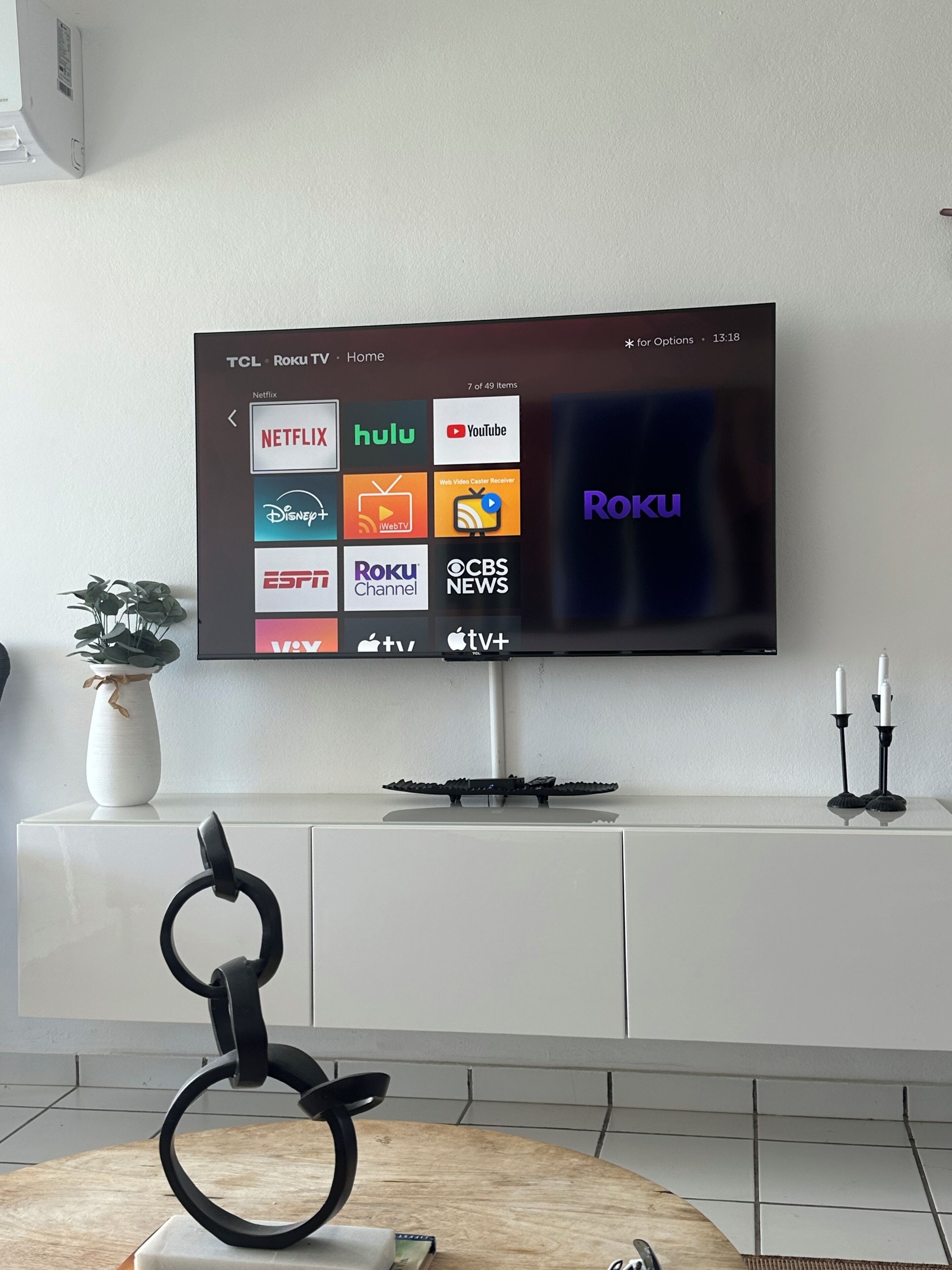 Televisor de pantalla plana penjat a la paret amb interfaç Roku que mostra diversos serveis de transmissió.