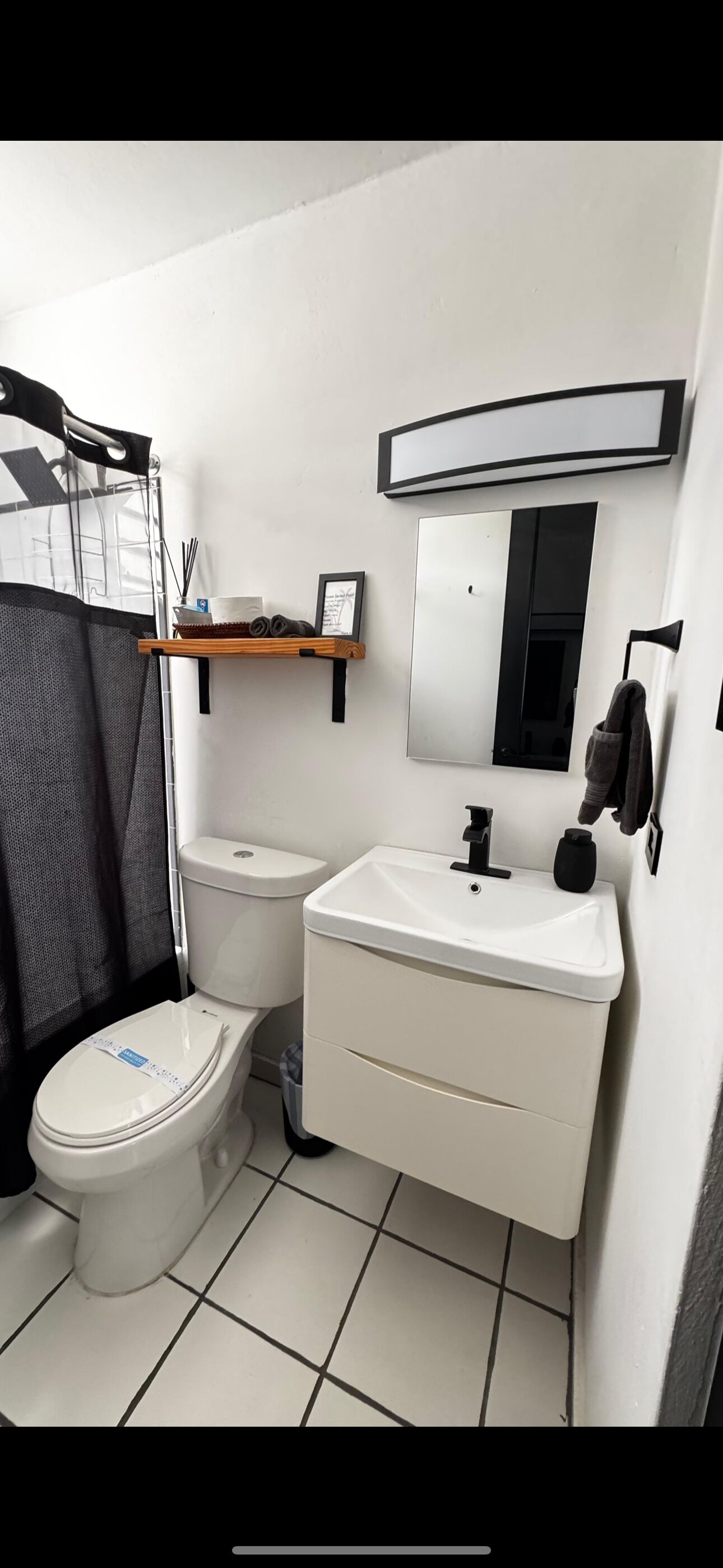 Et moderne badeværelse med toilet, håndvask, spejl og håndklædestang.