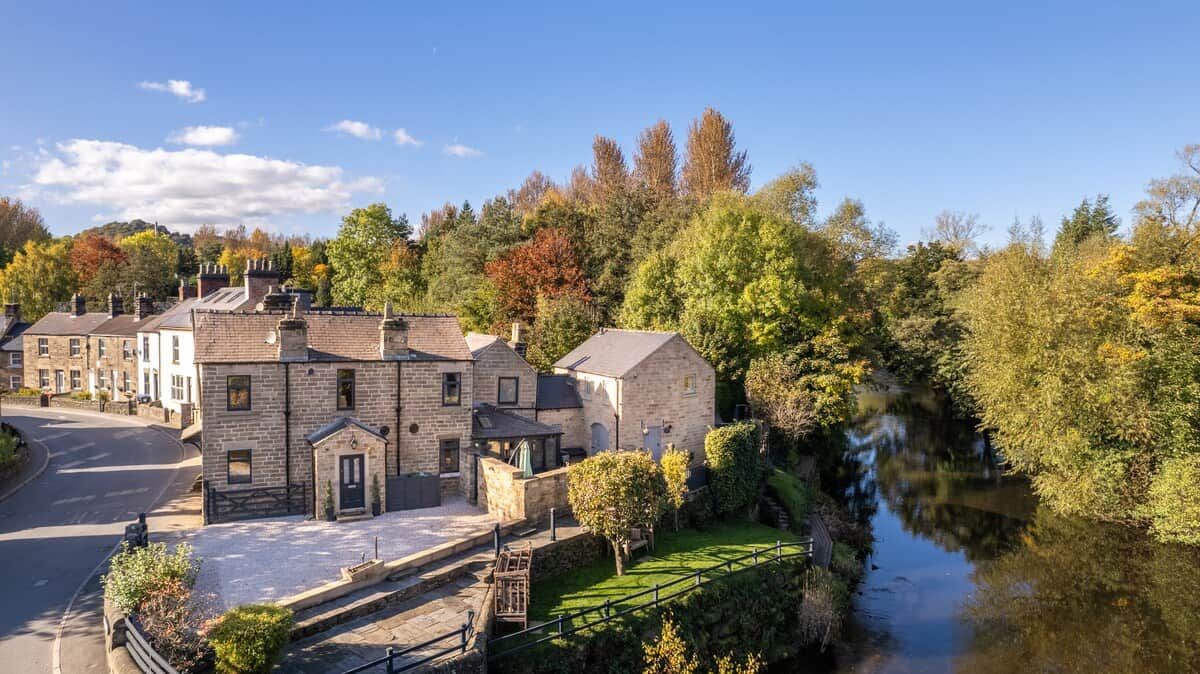 A stone building with a paved courtyard and a river in the background.