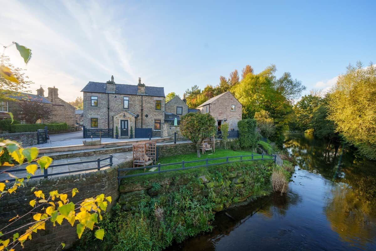 A stone building with a paved patio and a small bridge over a water channel.
