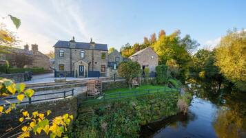 A stone building with a paved patio and a small bridge over a water channel.