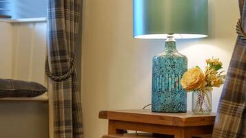 A room with a round wooden table, a lamp, and a vase with flowers.