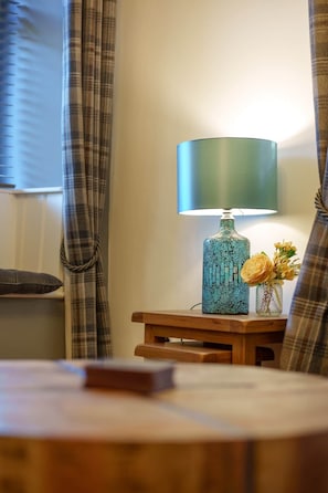 A room with a round wooden table, a lamp, and a vase with flowers. - Family Home | River Derwent | Hot tub | 10 guests (Darley Bridge)