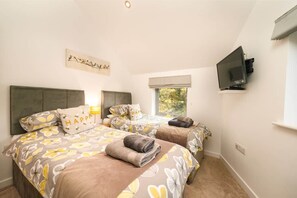 Een hotelkamer met twee bedden, een televisie, een raam en een schilderij aan de muur.